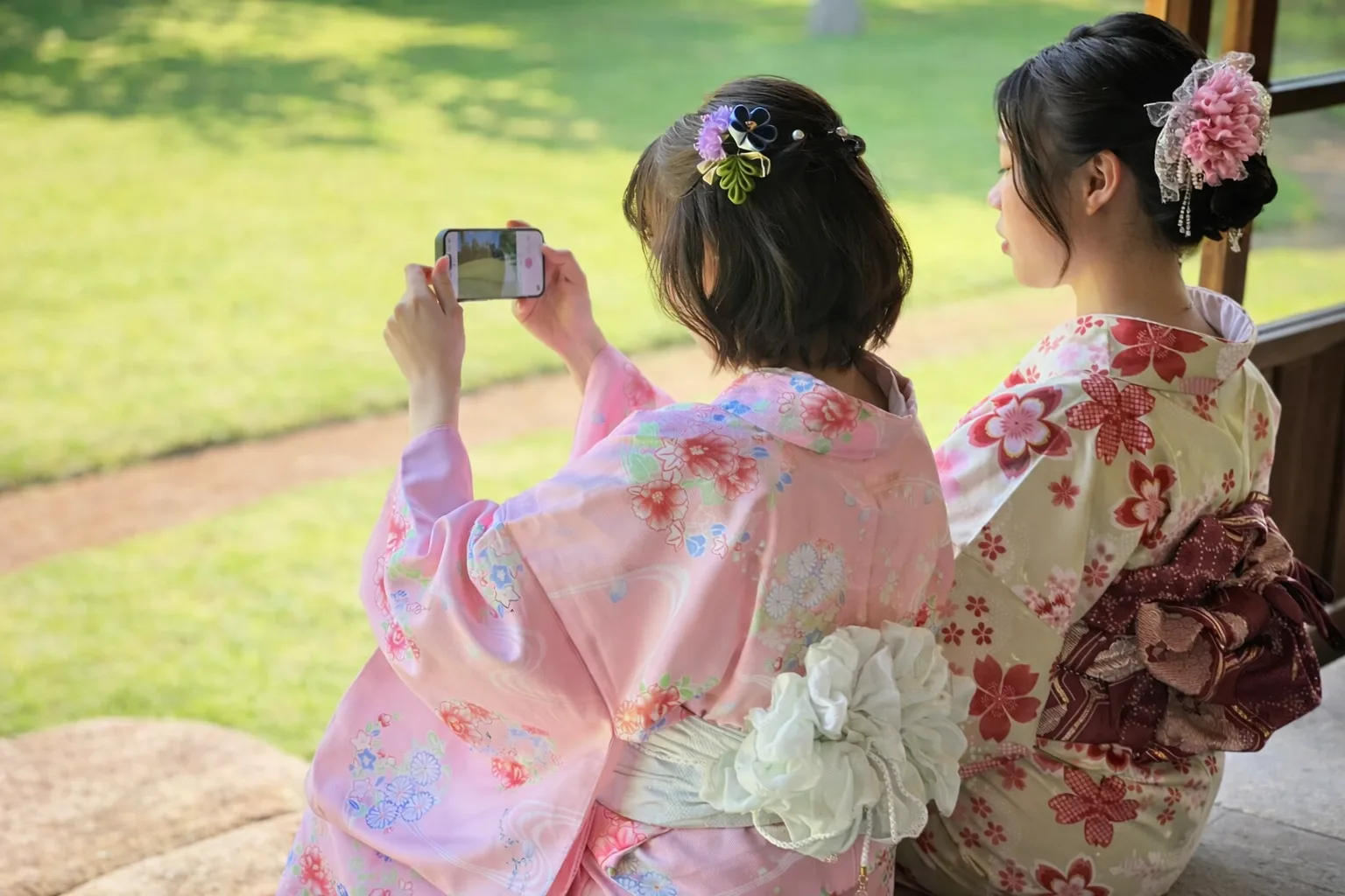 Two women in kimono taking photos in a park in Asakusa